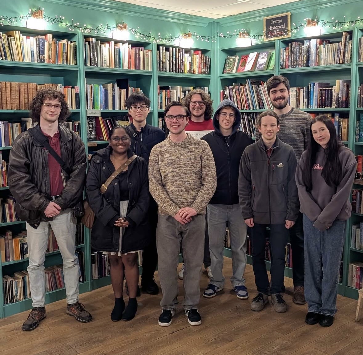 A group of students posing for a photo in front of a bookshelf.