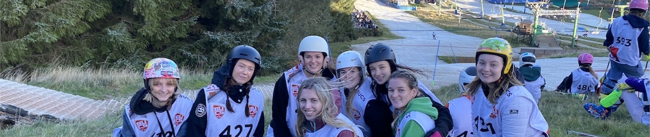 Group of people in ski gear smiling at the camera, there is a mountain behind them