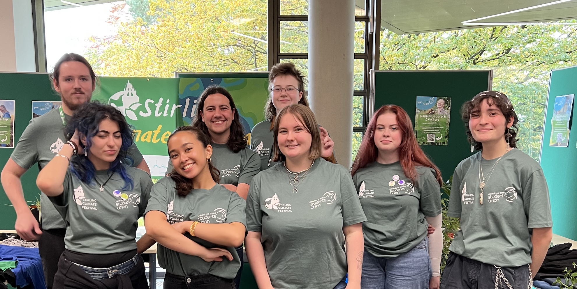 A group of students all wearing the same green tshirt standing smiling at the camera.