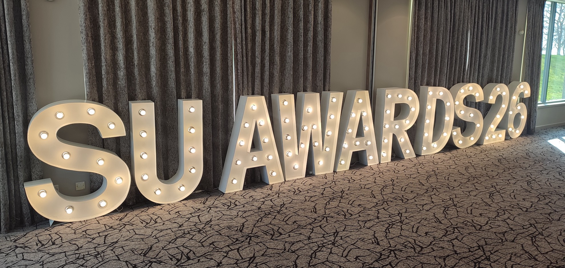 A big sign with lights in the letters that reads 'SU AWARDS 26'