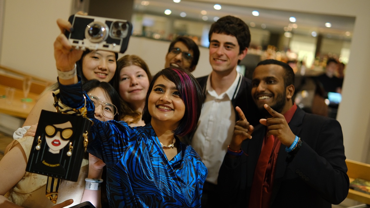 Group of people all dressed smartly taking a big group selfie together.